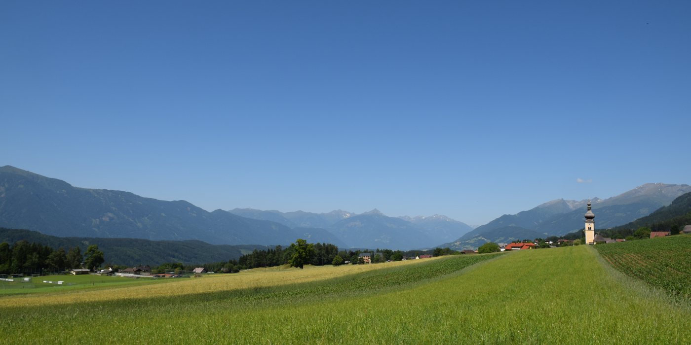 © © Foto: Daniel Oberzaucher; Sommer am Millstätter Berg, Blick über die Pfarrkirche zur Reißeckgruppe, links davon die Kreuzeckgruppe