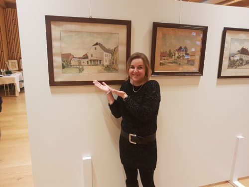 Frau Claudia Kueschnig vor einem Bild mit einem Gemischtwarengeschäft (Pfarrarchiv Neuhaus-Suha) Frau Claudia Kueschnig vor einem Bild mit einem Gemischtwarengeschäft (Pfarrarchiv Neuhaus-Suha)