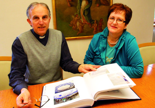 Dechant Josef Scharf blättert mit Melitta Käfer in der umfassenden Dokumentation zu ihrem Fastentuch. (© Foto: Foto: Eggenberger)