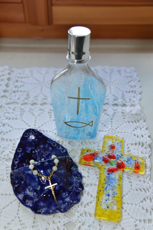 Ein Glaskreuz, ein Weihwasserbecken mit einem Rosenkranz und ein Fläschchen mit Weihwasser als Erinnerung an das große Fest. (© Foto: Michael Habernigg) Ein Glaskreuz, ein Weihwasserbecken mit einem Rosenkranz und ein Fläschchen mit Weihwasser als Erinnerung an das große Fest. (© Foto: Michael Habernigg)
