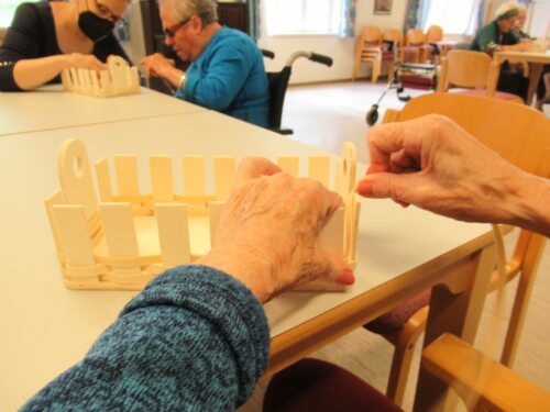<br />
Fördert Feinmotorik, weckt Erinnerungen: das Korbflechten. Im Bild Bewohnerin Irmgard Towet mit Eva-Maria Auberger (Foto: Caritas)