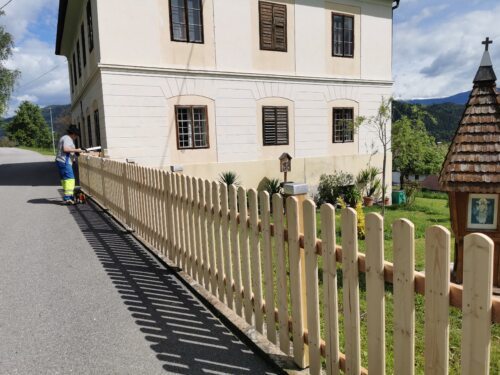 Erneuerung des Lattenzauns • Obnova plota pri župnišču (Foto: Pfarrarhiv Neuhaus- Suha) Erneuerung des Lattenzauns • Obnova plota pri župnišču (Foto: Pfarrarhiv Neuhaus- Suha)