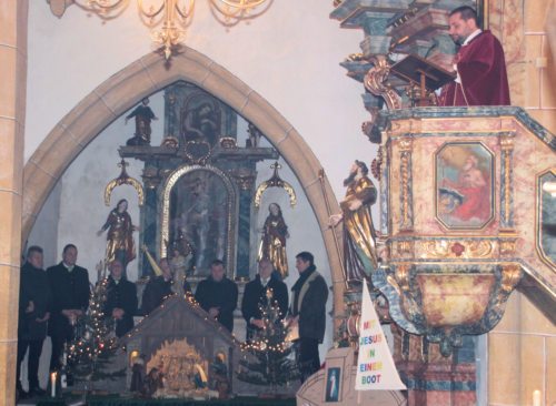 Hl. Messe – Provisor Mrawczynski bei der Predigt, MGV Tratten (davor Weihnachtskrippe).